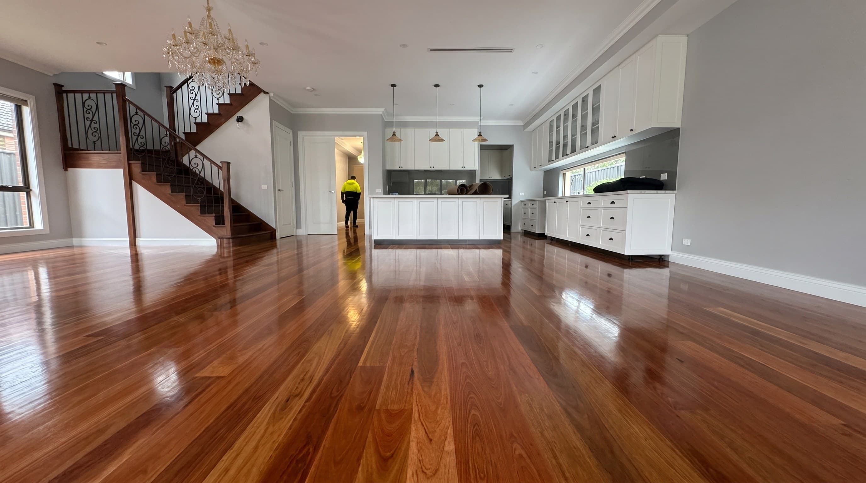 Freshly polished timber floor running through an open-plan living area, staircase and kitchen