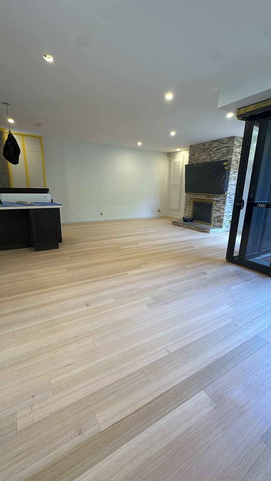 Wide blonde timber boards running through an open-plan living and kitchen area